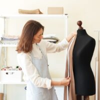 The seamstress measures the fabric on the mannequin